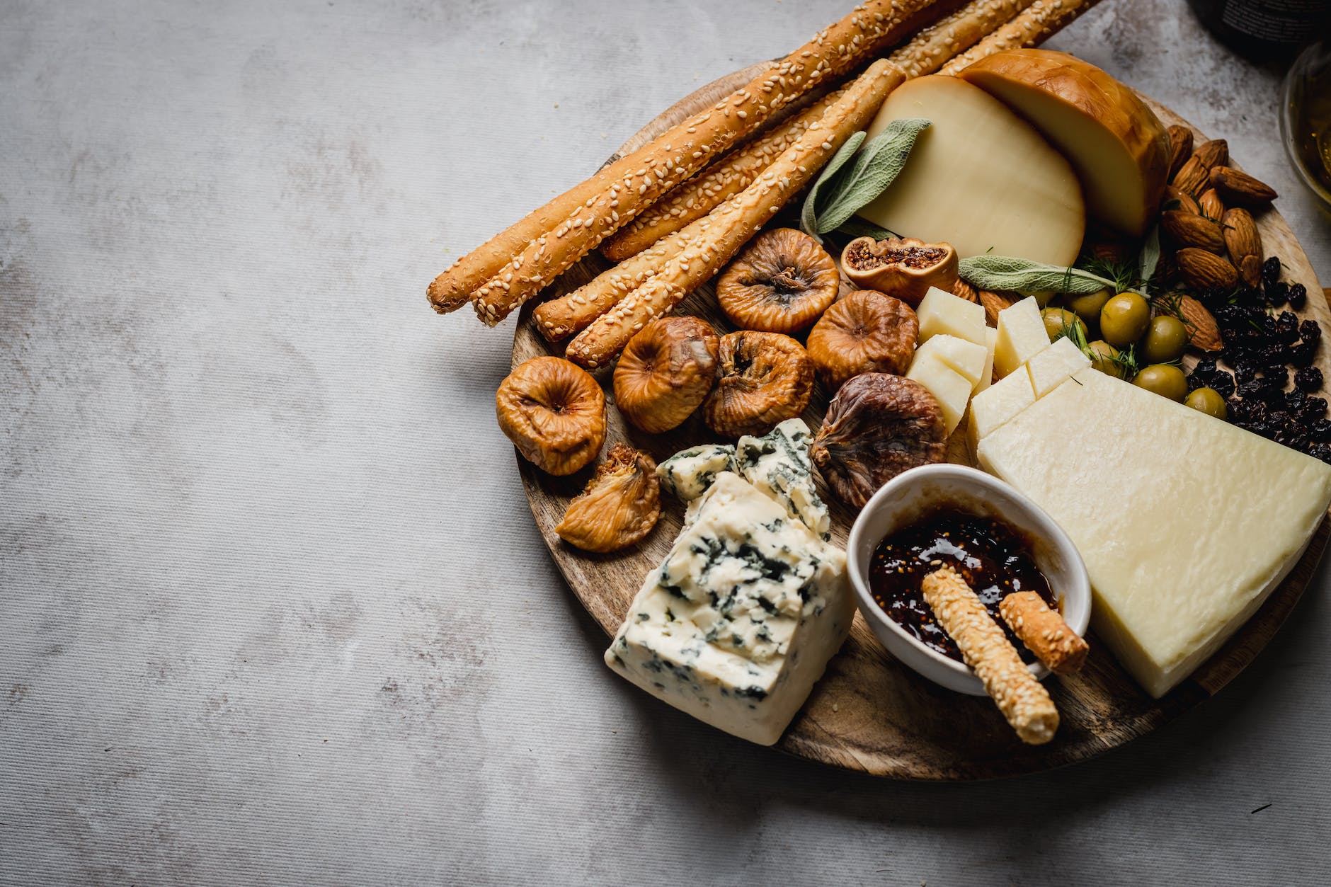 assorted cheese and nuts on the wooden platter